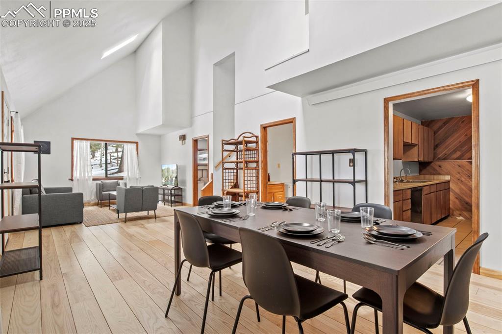 Image 17 of 50: Dining space with high vaulted ceiling, stairway, and light wood-type floor