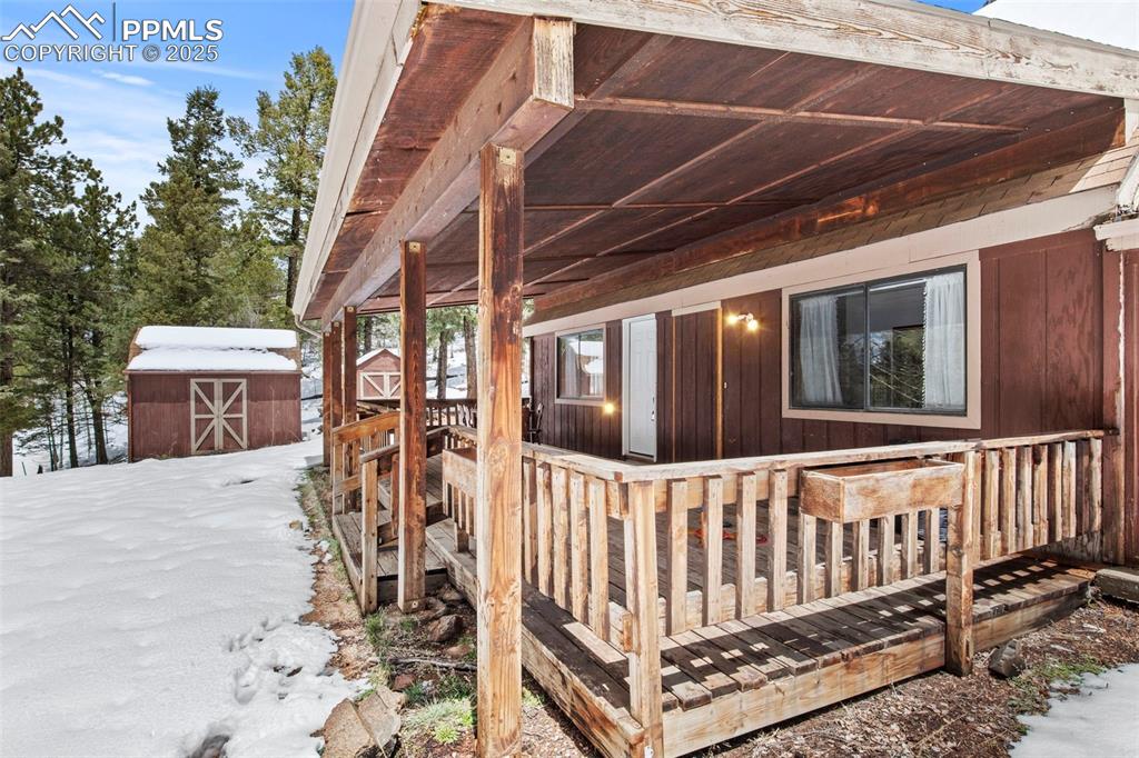 Image 2 of 50: View of snow covered exterior featuring a deck and a storage shed