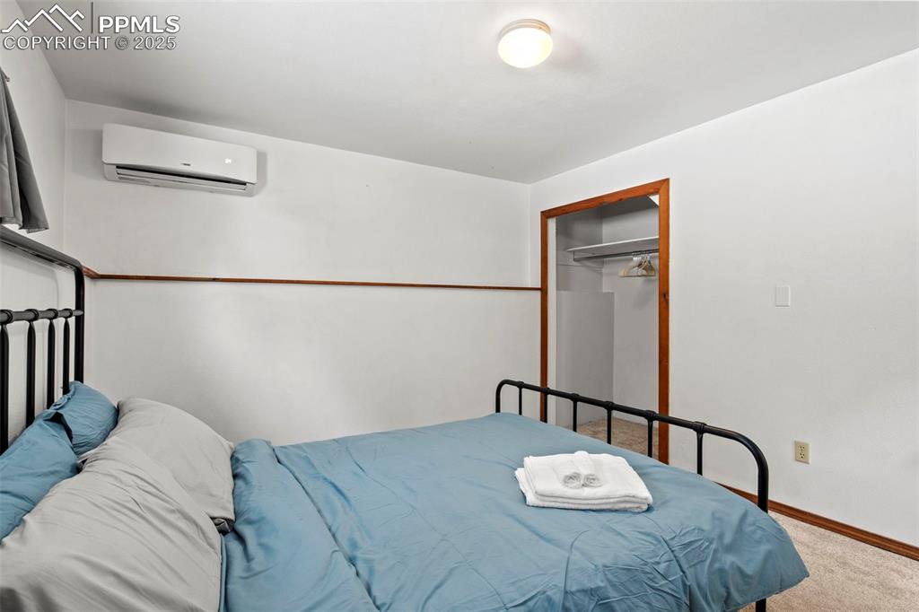 Image 27 of 50: Bedroom featuring a closet, a wall mounted air conditioner, and carpet