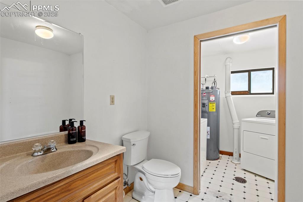 Image 29 of 50: Bathroom featuring washer / dryer, vanity, and electric water heater