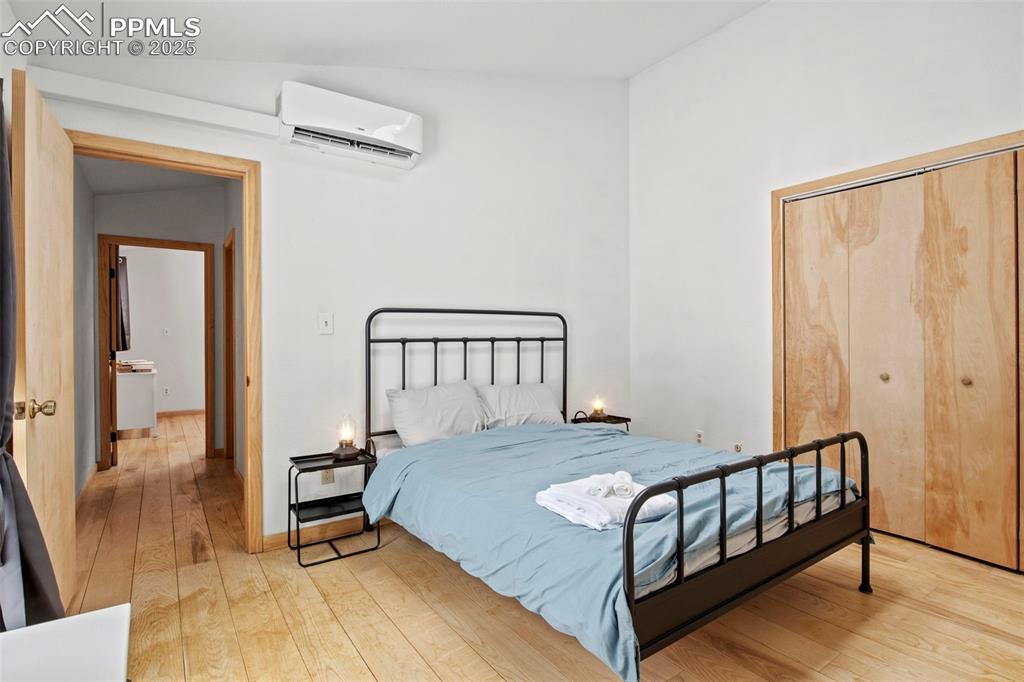 Image 33 of 50: Bedroom with light wood-style floors, a wall mounted AC, and a closet