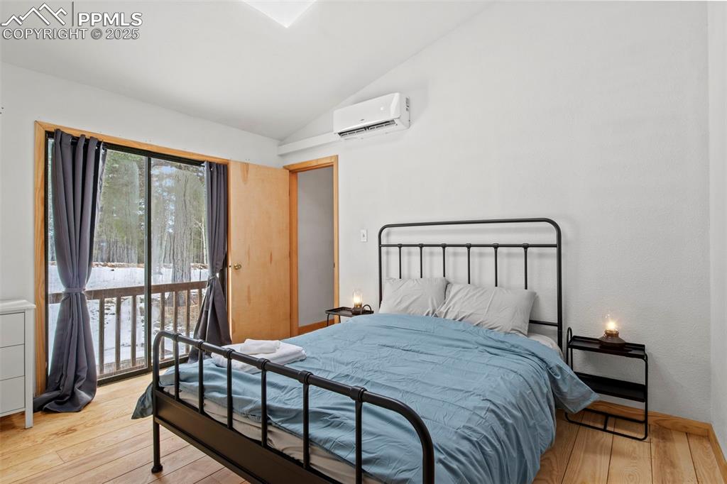 Image 35 of 50: Bedroom with vaulted ceiling, light wood-style floors, access to outside, a