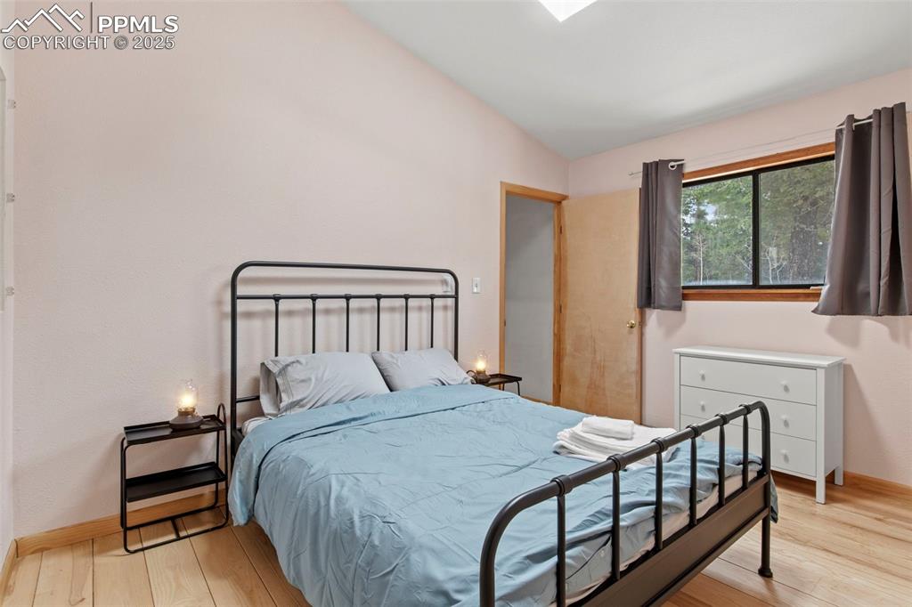 Image 42 of 50: Bedroom with light wood-style flooring and vaulted ceiling