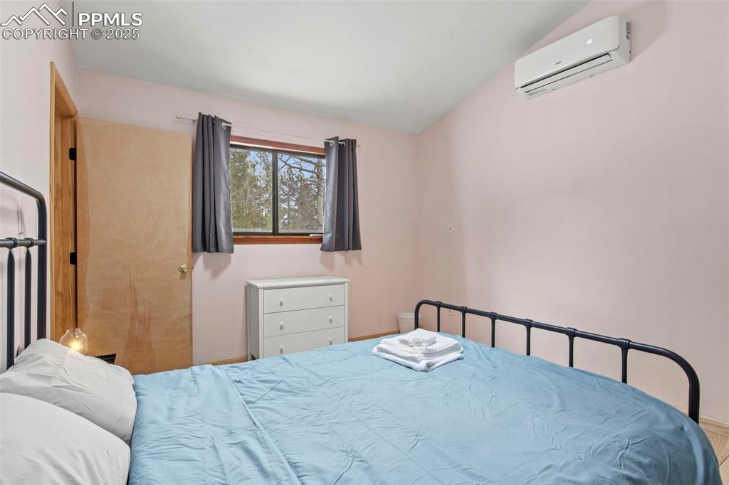 Image 43 of 50: Bedroom featuring an AC wall unit and lofted ceiling