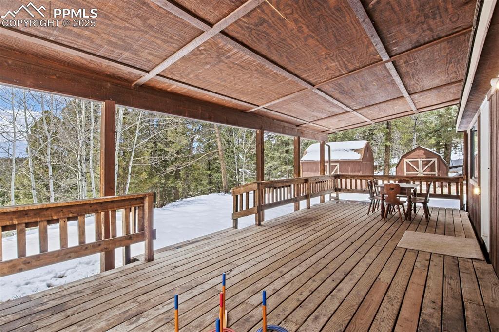 Image 47 of 50: Snow covered deck with a storage unit and outdoor dining space