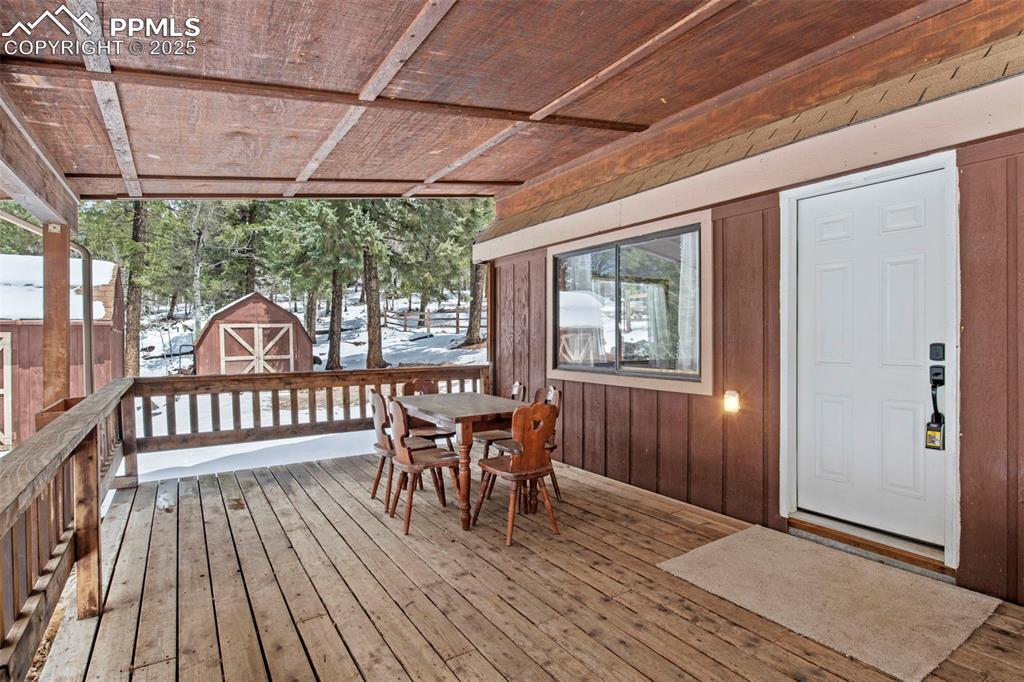Image 6 of 50: Snow covered deck featuring outdoor dining space and a storage unit