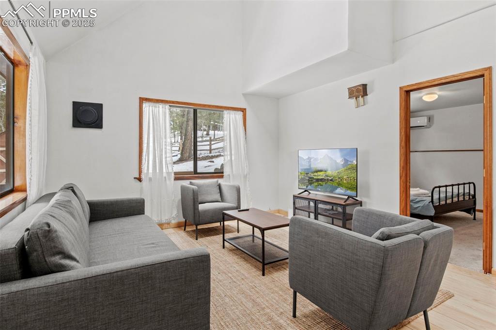 Image 9 of 50: Living room featuring high vaulted ceiling and light wood-style floors