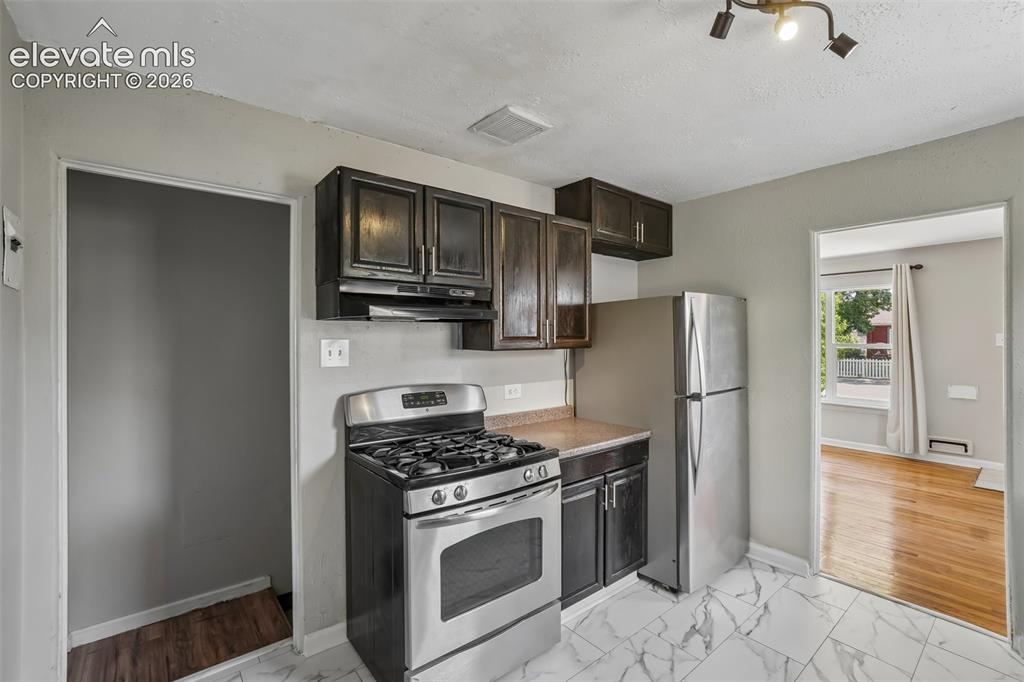 Image 10 of 33: Kitchen featuring stainless steel range, stainless steel refrigerator, dark
