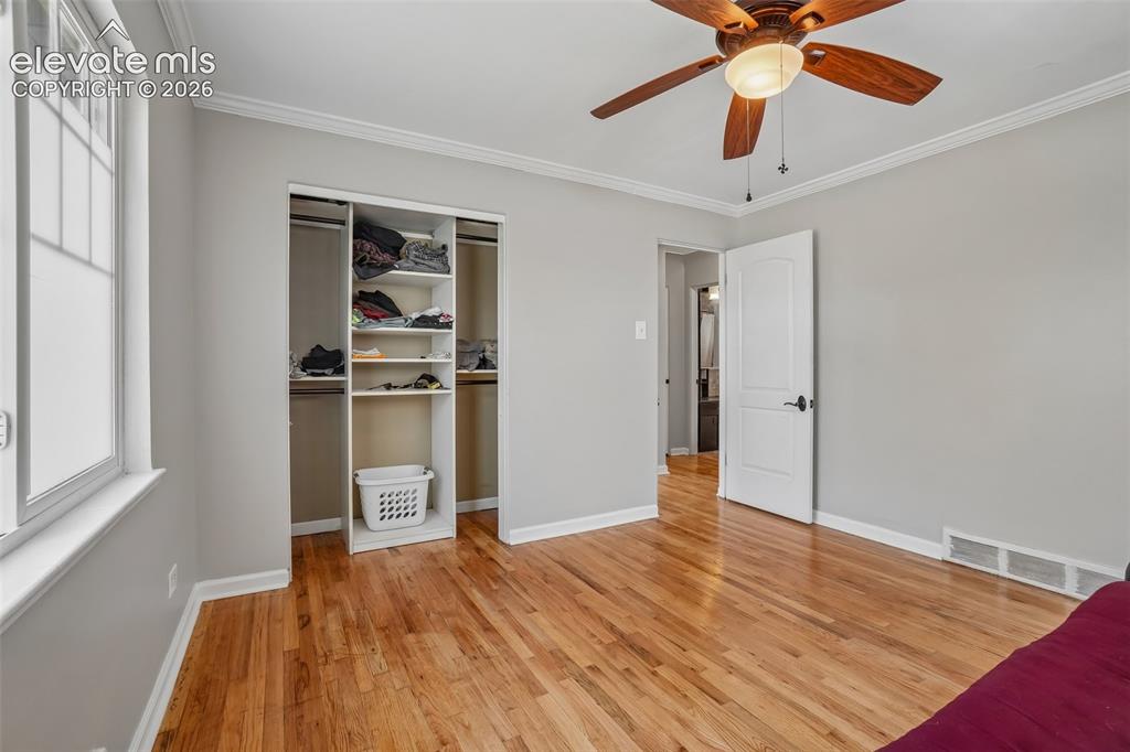 Image 11 of 34: Wood-finish flooring with crown molding, a built-in closet system, and a ce