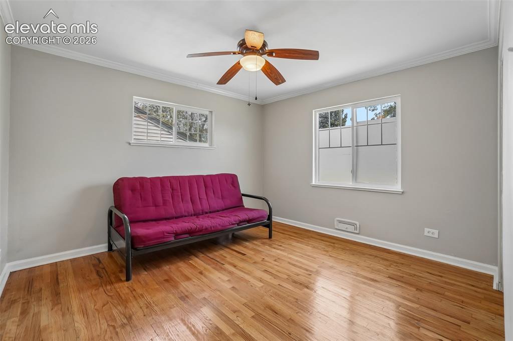 Image 12 of 34: Hardwood flooring, two windows, crown molding, and a ceiling fan with integ