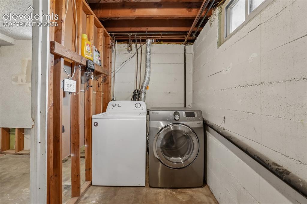 Image 19 of 34: Laundry area featuring a top-load washer, a front-load dryer, and a high-se