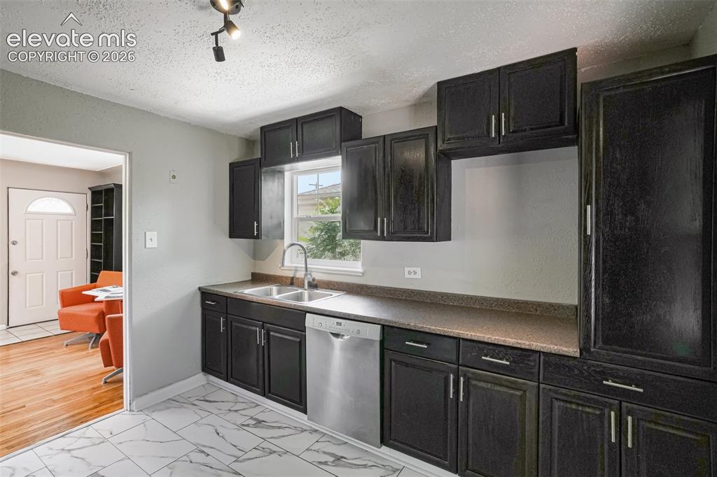 Image 2 of 34: Kitchen featuring dark wood-finish cabinetry, stainless steel dishwasher, d