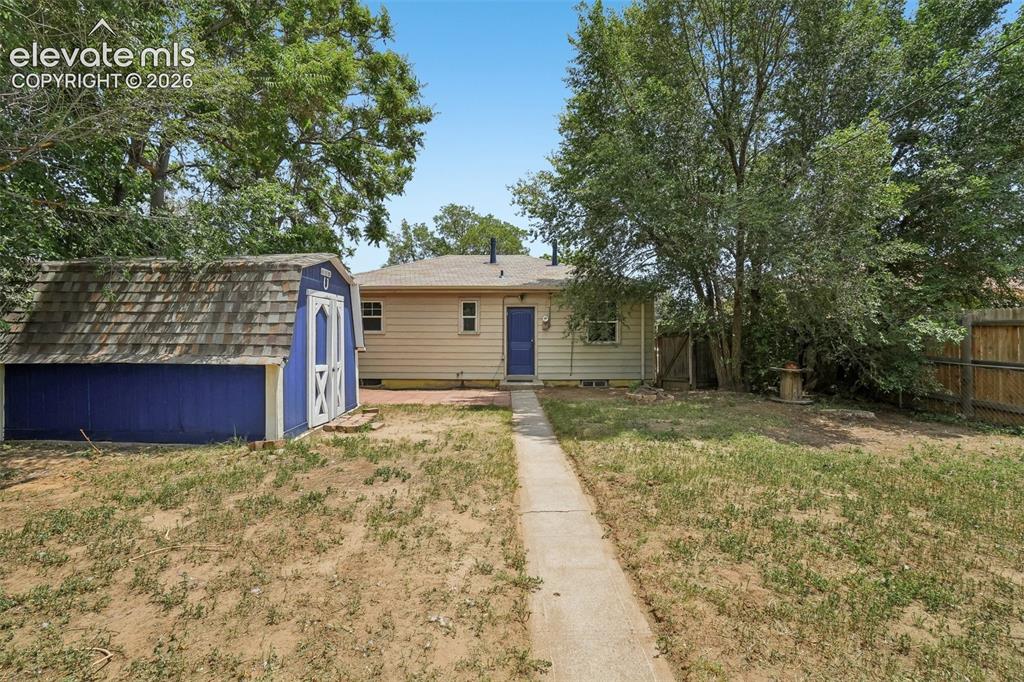 Image 25 of 34: Rear exterior of the residence with a blue storage shed, concrete pathway,