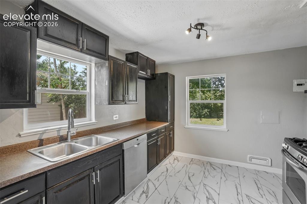 Image 9 of 33: Kitchen featuring dark wood-finish cabinetry, a double basin stainless stee