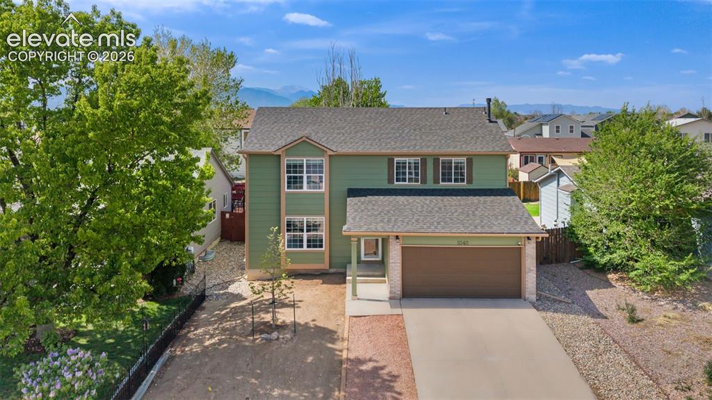 Caption: Two-story home featuring a two-car garage, light green siding, and a partial stone facade
