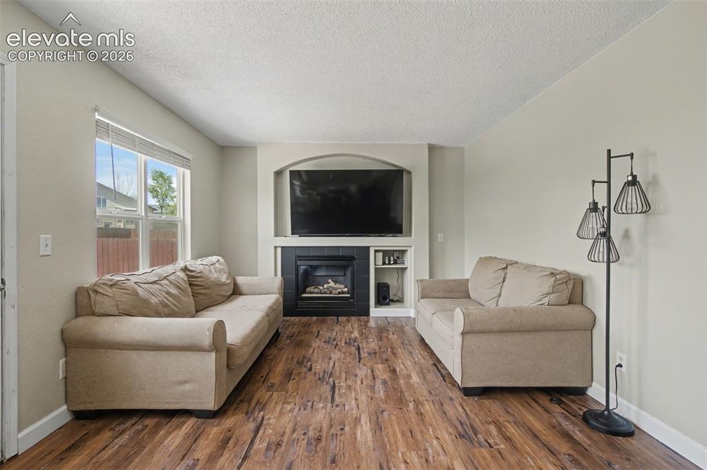 Image 19 of 37: Living area featuring wood-finish flooring, a built-in fireplace with a bla