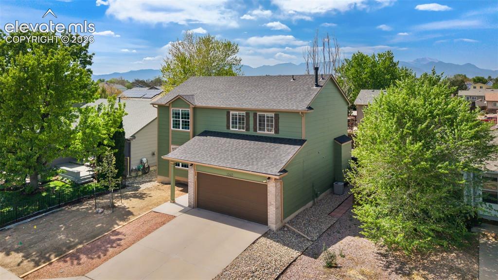 Image 2 of 37: Two-story home featuring a green exterior, an attached garage, and a concre