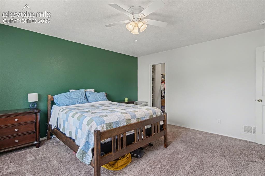 Image 21 of 37: Carpeted bedroom featuring a ceiling fan, accent wall, and a built-in close