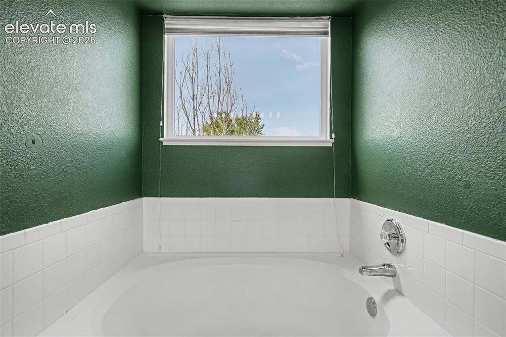 Image 23 of 37: Bathtub featuring a white basin, chrome fixtures, and white subway tile sur