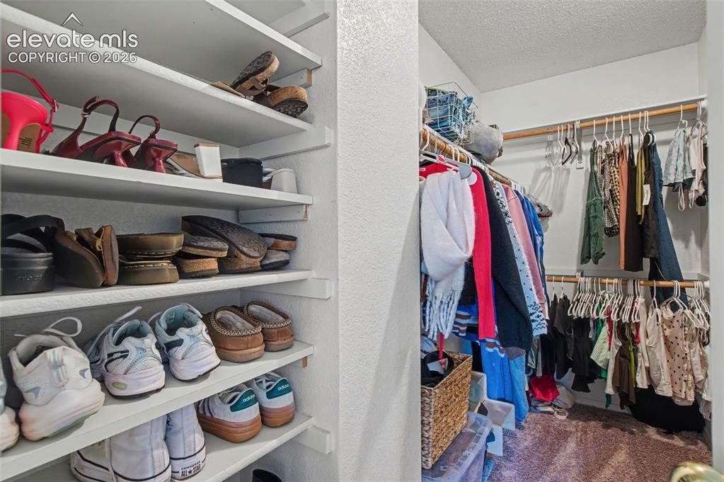 Image 24 of 37: Walk-in closet featuring extensive built-in shelving, multiple hanging rods