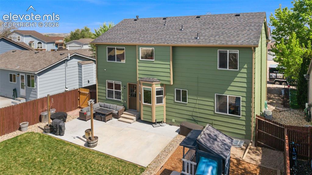 Image 3 of 37: Rear exterior featuring a spacious concrete patio, private yard, and multi-