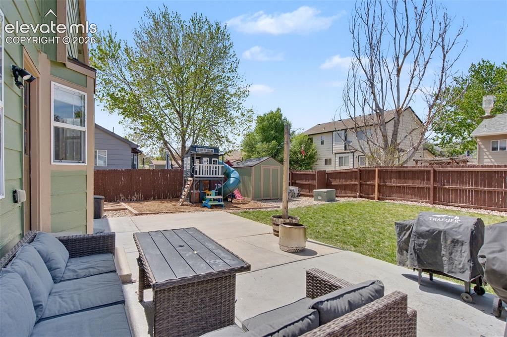 Image 33 of 37: Expansive concrete patio area with a manicured lawn