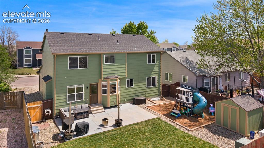 Image 34 of 37: Expansive backyard featuring a large concrete patio, a green two-story exte