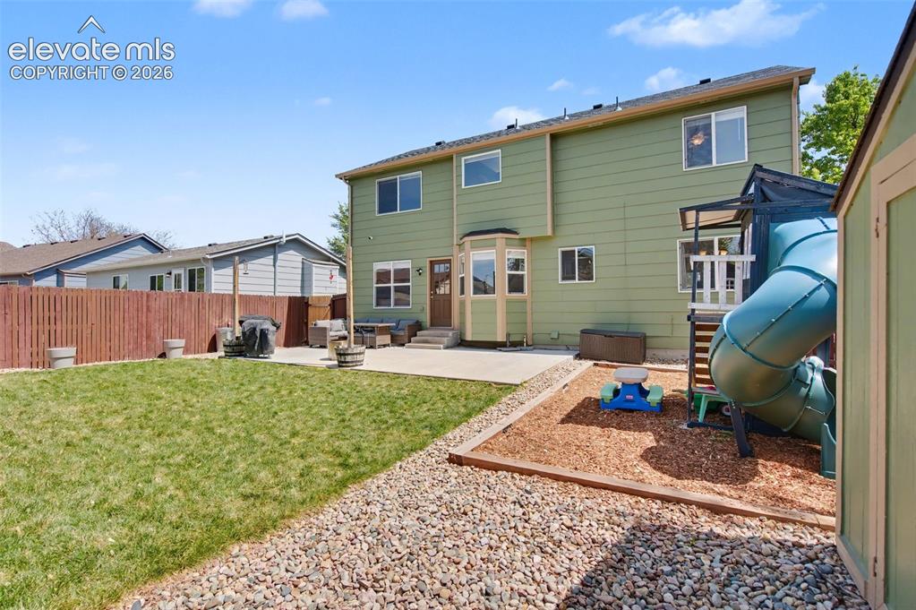 Image 36 of 37: Expansive backyard featuring a green lawn, concrete patio, and a dedicated 