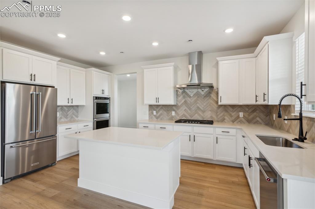 Image 2 of 19: Kitchen featuring a sink, a kitchen island, wall chimney exhaust hood, appl