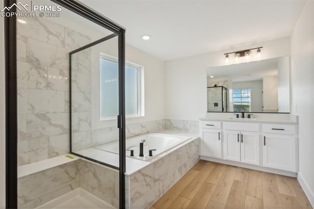 Image 7 of 19: Bathroom featuring a bath, vanity, wood finished floors, and a shower stall
