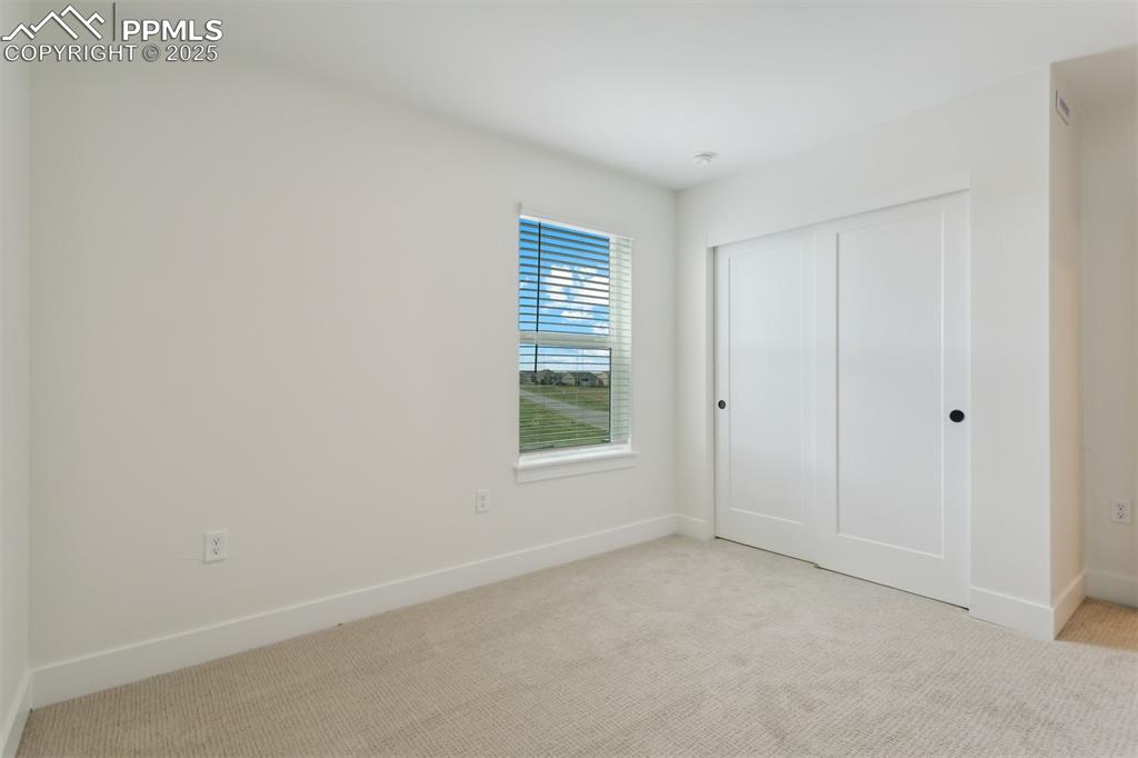 Image 9 of 19: Unfurnished bedroom with carpet floors, baseboards, and a closet