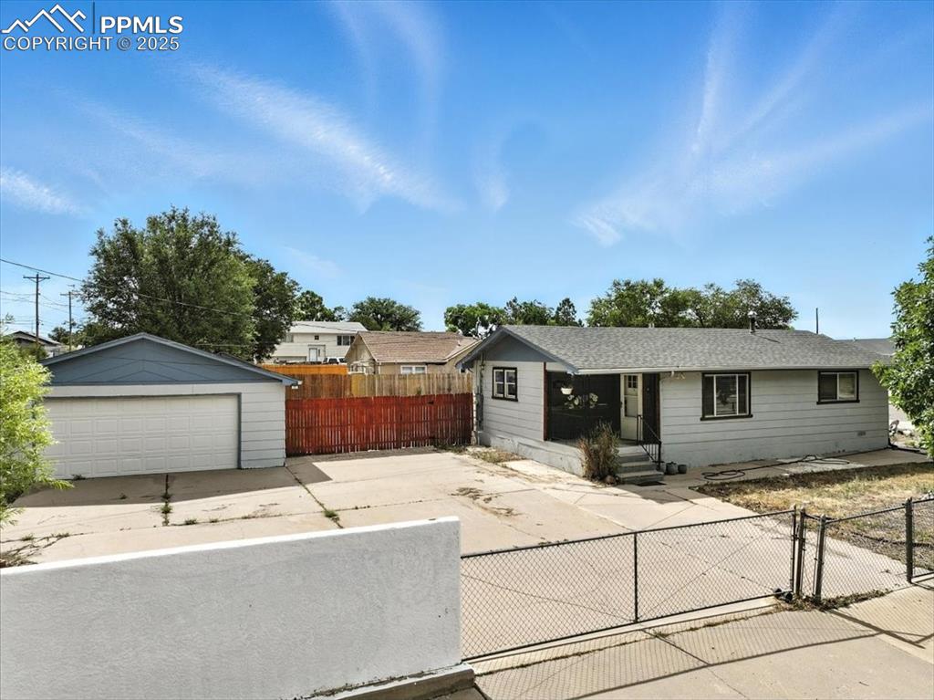 Caption: Ranch-style house with a garage, an outbuilding, and a gate