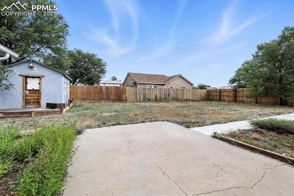 Image 27 of 30: Fenced backyard with a patio area and an outbuilding