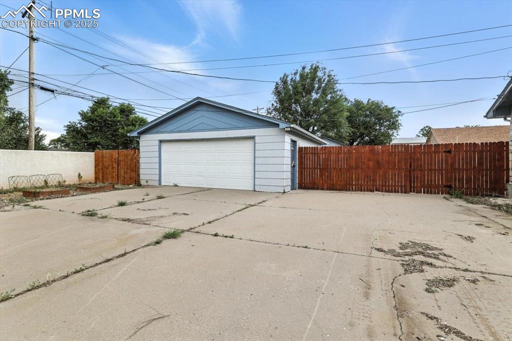 Image 31 of 32: Fenced backyard with a patio area and an outbuilding