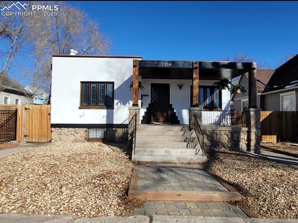 Caption: View of front of property featuring stucco siding, a gate, and covered porch