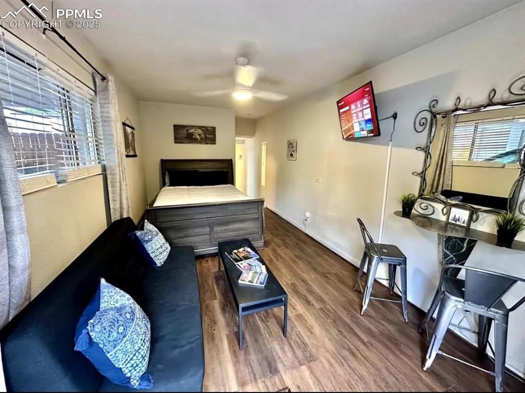 Image 12 of 16: Bedroom with multiple windows, dark wood-style floors, and a ceiling fan