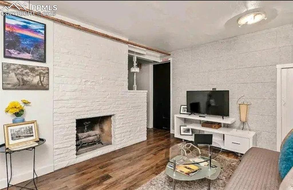 Image 16 of 16: Living room featuring wood finished floors and a fireplace