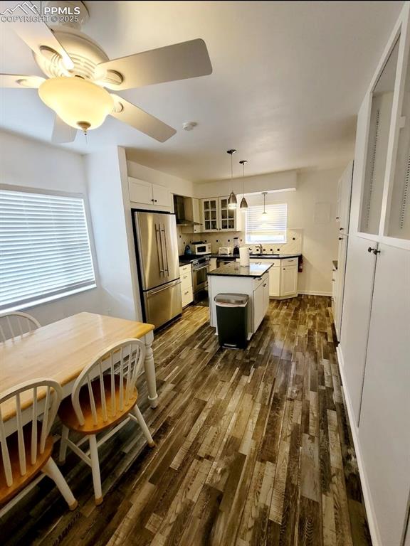Image 7 of 16: Kitchen with dark countertops, stainless steel appliances, white cabinets,