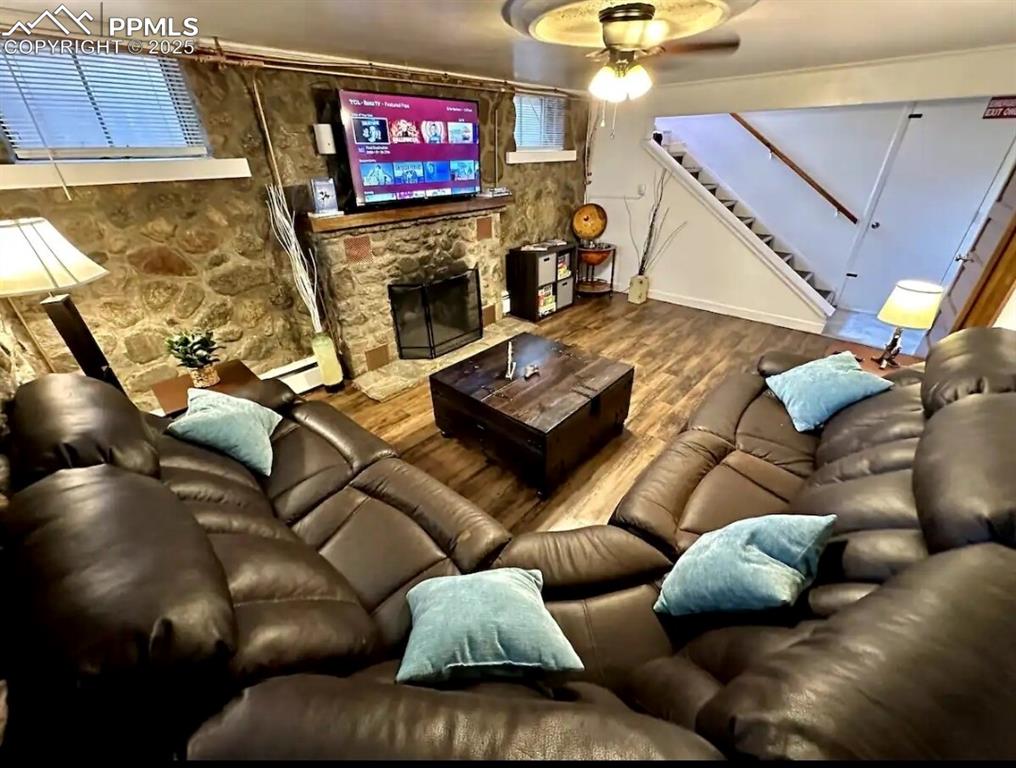 Image 8 of 16: Living room featuring a ceiling fan, stairway, wood finished floors, and a