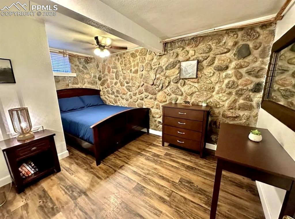 Image 9 of 16: Bedroom with wood finished floors, a textured ceiling, ceiling fan, and bea
