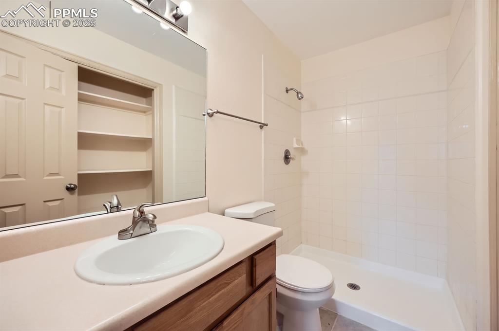 Image 17 of 31: Bathroom with a tile shower, toilet, and vanity