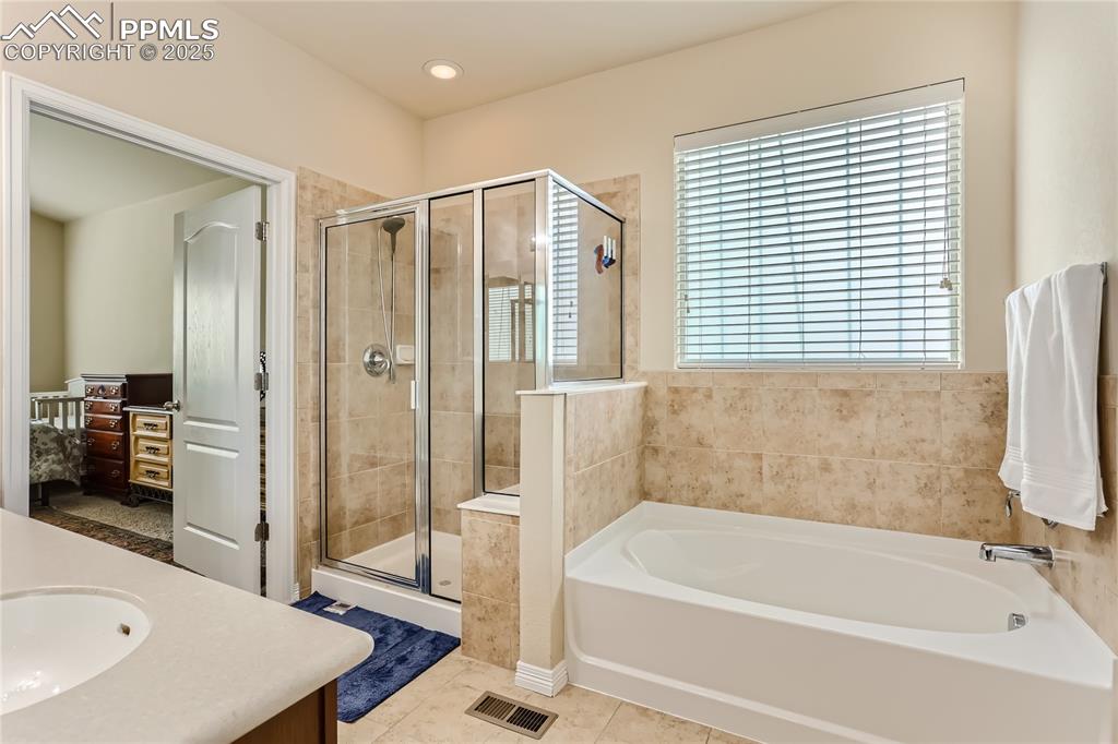 Image 14 of 28: Bathroom with a stall shower, visible vents, tile patterned flooring, vanit
