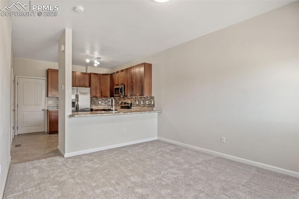 Image 11 of 41: Kitchen featuring backsplash, light colored carpet, stainless steel applian
