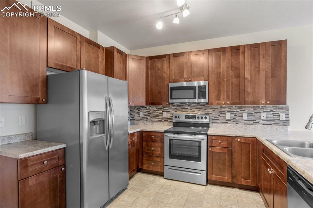 Image 12 of 41: Kitchen with appliances with stainless steel finishes, light countertops, t