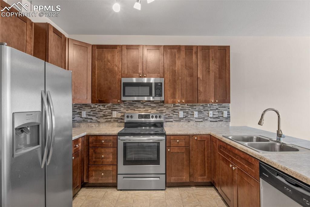 Image 13 of 41: Kitchen with stainless steel appliances, decorative backsplash, brown cabin