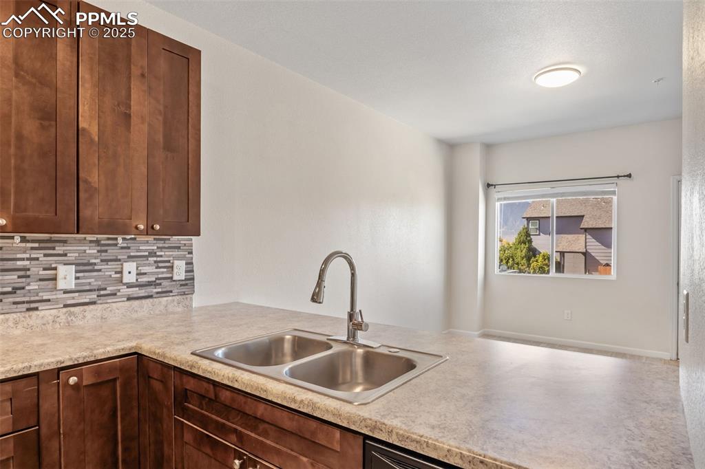 Image 15 of 41: Kitchen featuring light countertops, tasteful backsplash, and dark brown ca