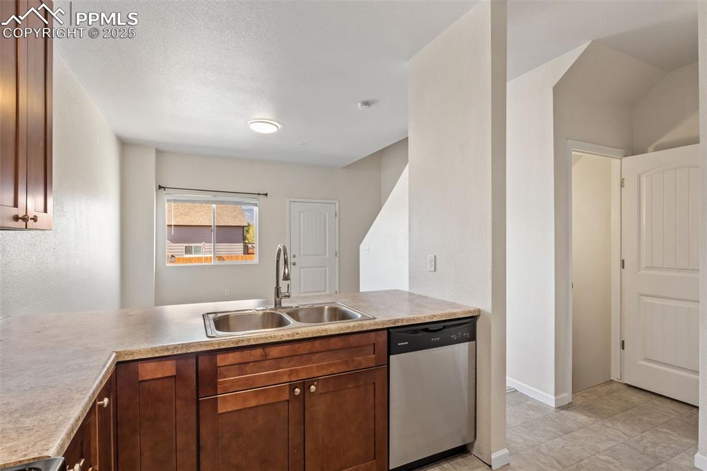 Image 17 of 41: Kitchen with stainless steel dishwasher, light countertops, and brown cabin