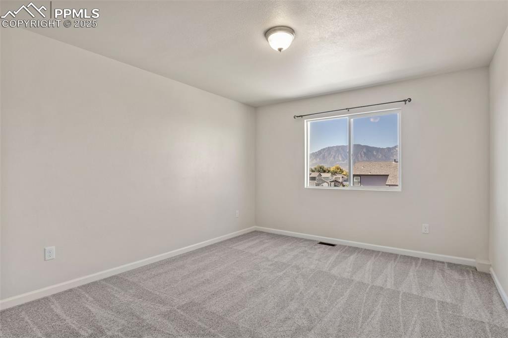 Image 19 of 41: Empty room featuring light colored carpet and a mountain view