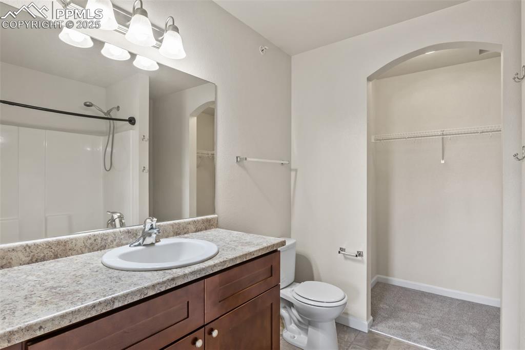 Image 24 of 41: Full bath featuring a walk in closet, vanity, light tile patterned flooring
