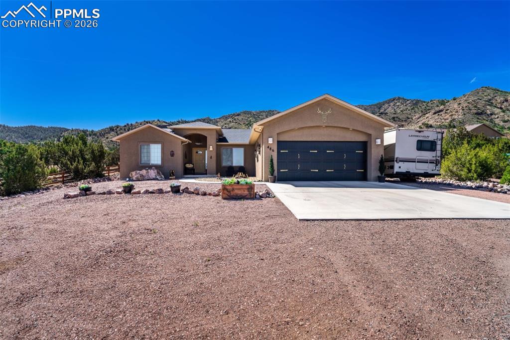 Image 2 of 50: Single story home with a mountain view, concrete driveway, a garage, and st